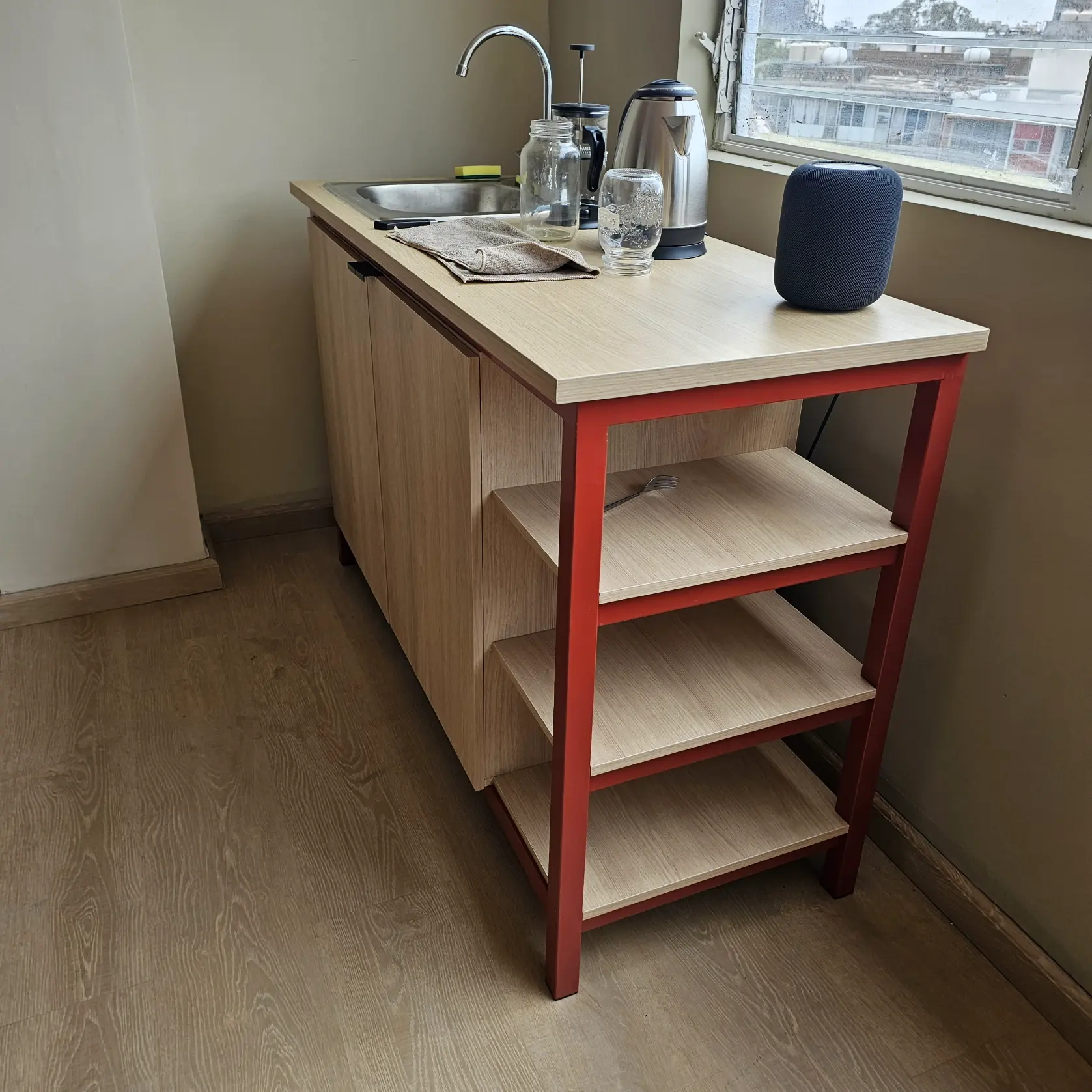 Barra de cocina integral con fregadero, repisas abiertas y estructura metálica roja